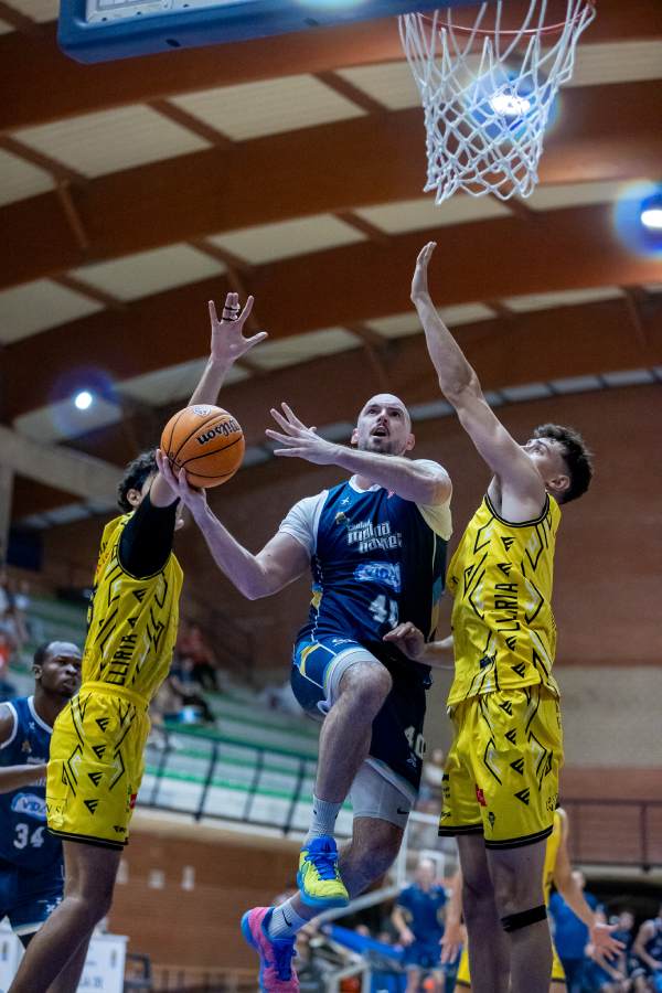 Jugador Molina basket en medio tratando de encestar con dos jujadores contrarios